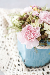 Bouquet of pink carnations and yellow Kalanchoe blossfeldiana flowers in blue ceramic vase.