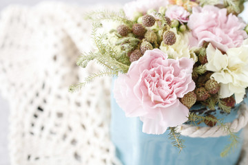 Bouquet of pink carnations and yellow Kalanchoe blossfeldiana flowers in blue ceramic vase.