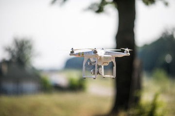 Quadrocopter drone with the camera. Copter flying against green blurred background.