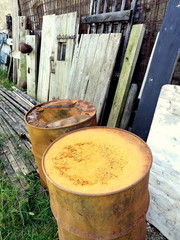 Alte rostige Fässer und alte Holztüren vor einem ehemaligen Kuhstall eines Bauernhof im Sommer im...