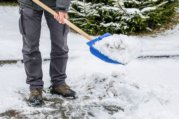 Man removing snow from the sidewalk after snowstorm