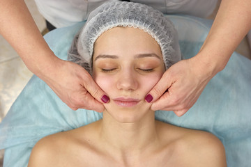 Girl getting face massage. Hands of cosmetician, young female.
