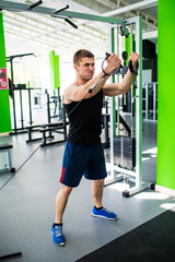 Fototapeta premium Handsome man exercising in trainer for triceps muscles in the gym