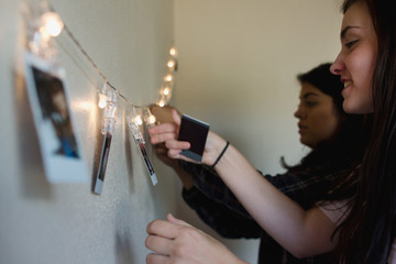 teenagers hang  pictures on lighted string