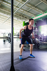 Fototapeta premium Close up of young muscular man lifting weights over gym background