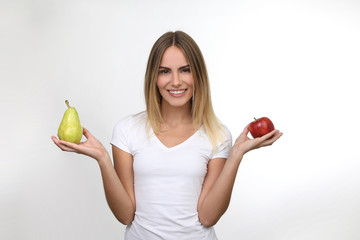 Hübsche blonde Frau mit Apfel und Birne in den Händen lacht