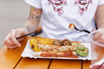 The local food festival. A beautiful girl eats fried sausages and vegetables