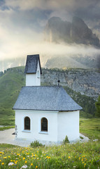 alone church under mountains in clouds in the morning in Italy