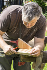 Close-up of craftsman hands measuring wooden plank with ruler and pencil. Concept of woodwork and handcraft.