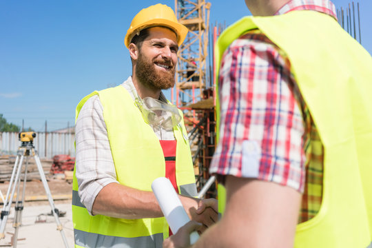 Cheerful construction worker shaking the hand of an architect or a foreman as a gesture of agreement, and partnership at the beginning of a new project