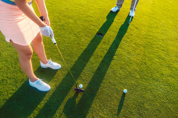 High-angle cropped view of a professional woman player holding the putter golf club, ready to hit...