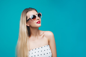 Summer model portrait. Dressed well stylish girl on sunglasses on blue turquoise background. Cheerful young woman on white dress.