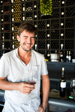Young man laughing while holding a glass of wine on a winery