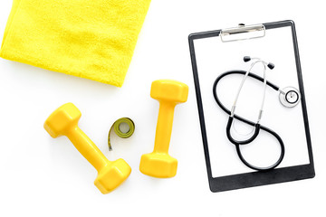 Sport and health. Fitness. Dumbbells and stethoscope on white background top view