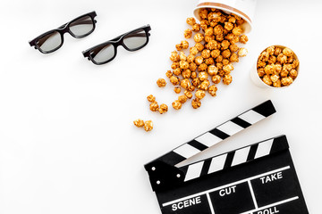 To go to the cinema. Clapperboard, glasses and popcorn on white background top view copyspace