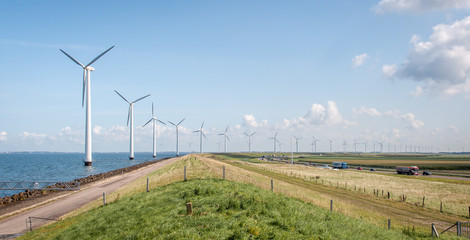 Long row of windmills next to the road, with a lot of traffic