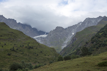Fototapeta na wymiar Горный пейзаж. Пасмурная погода в живописном ущелье, туман в горах, белые облака. Природа Северного Кавказа