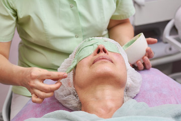 Obraz na płótnie Canvas Cosmetician applying alginate face mask. Adult woman, cosmetology procedure. Algae based cosmetics.