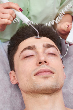 Male face, microcurrent therapy. Guy at the cosmetician. How effective is skin electrotherapy.