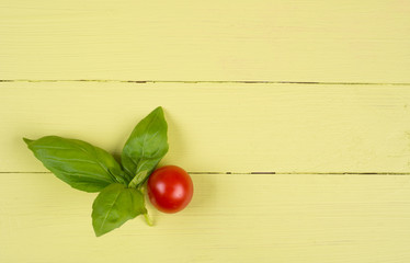 Naklejka na ściany i meble Basil leaves and tomato on yellow table