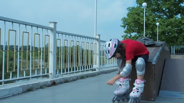 The child wears roller skates. A little girl in roller skates on the river bank.