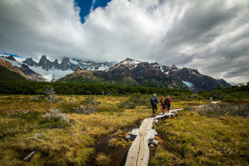 Naklejka premium Tourists are walking along a wooden bridge over a swamp. Shevelev.