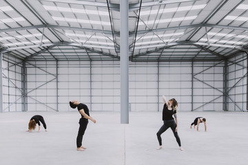 Four dancers exploring movement in a spacious empty warehouse