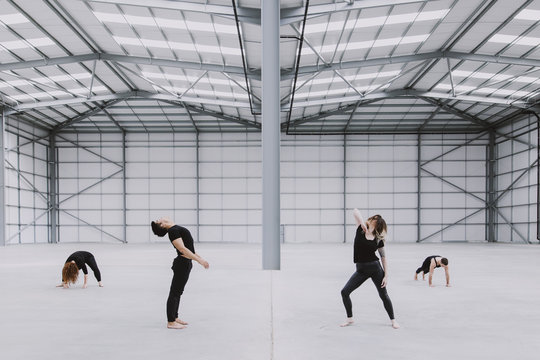 Four dancers exploring movement in a spacious empty warehouse - Powered by Adobe