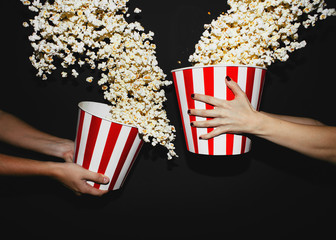 Close up of a man's and woman's hands holding two boxes of popcorn