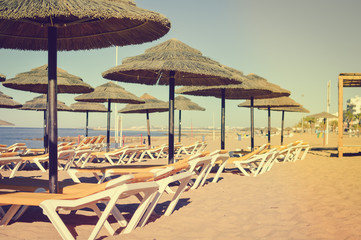 Sunny sky and chairs with parasol on the beautiful beach of Portugal