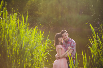 Lovers in a lake. Young couple in love sitting on the park ground near the water while these young...