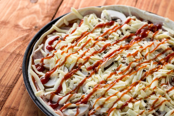 Round raw pizza with mushrooms and ketchup ready for baking