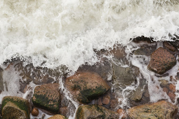 Aerial top view of sea waves hitting rocks