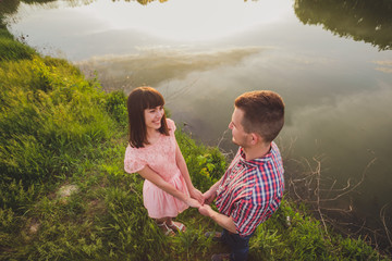 Lovers in a lake. Young couple in love sitting on the park ground near the water while these young...