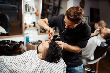 Obraz na płótnie Canvas Hairdresser doing correction and cutting bread in modern barbershop.