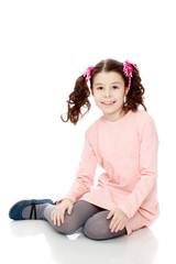 Little girl sitting on the floor and straightens hair.