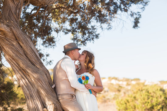 Newlywed couple standing under shade of tree in summer