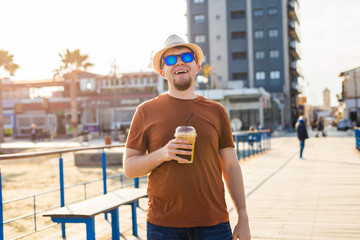 Handsome hipster man with paper coffee cup on street