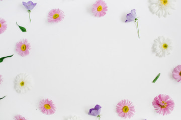 Naklejka na ściany i meble Floral frame with space for text made of white and pink chamomile daisy flowers, green leaves on white background. Flat lay, top view. Daisy background. Mock up frame of flower buds.