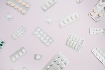 Flat lay medicine pills on pink background. Top view medical texture.