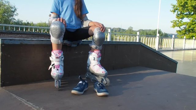 Legs of the child in the rollers. Legs in white rollers and denim sneakers.