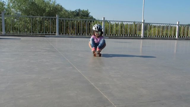 A child skates sitting on a skateboard. Little girl on skateboard.