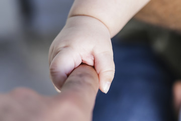 The father is holding the hand of the baby . Mother's and baby's hands. Family concept