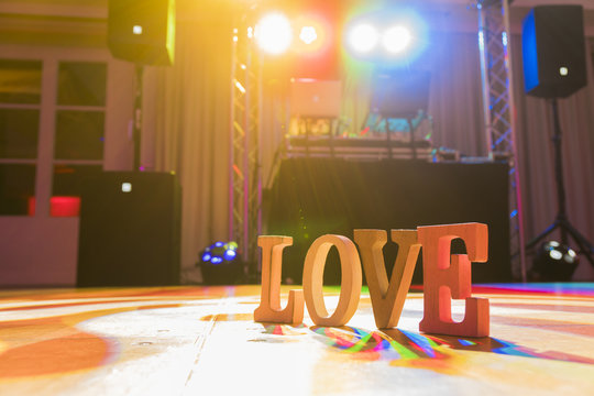 Hölzerndes Schild "Love" auf einer Tanzfläche von einem DJ nach der Hochzeitsfeier
