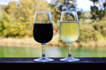 Two glasses of red and white wine on wooden rail