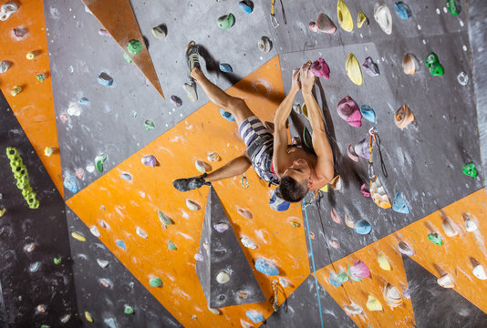 Young male rock climber in indoor climbing gym