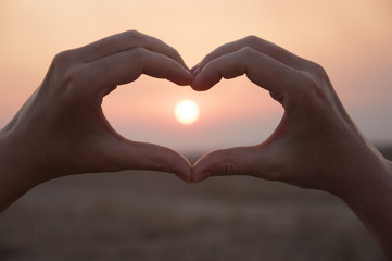 Hand shaped heart against a beautiful sunset