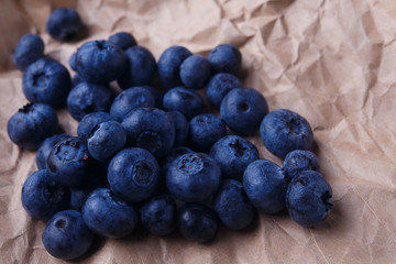 Blueberries on rustic wooden background, close up. Delicious berries on craft paper, macro