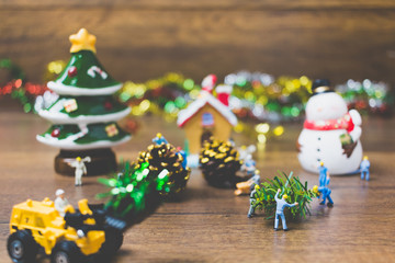 Creative concept with miniature people creating Christmas decorations on a wooden background.