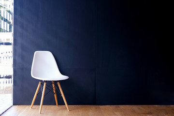 White chair in interior room  with dark blue wall.